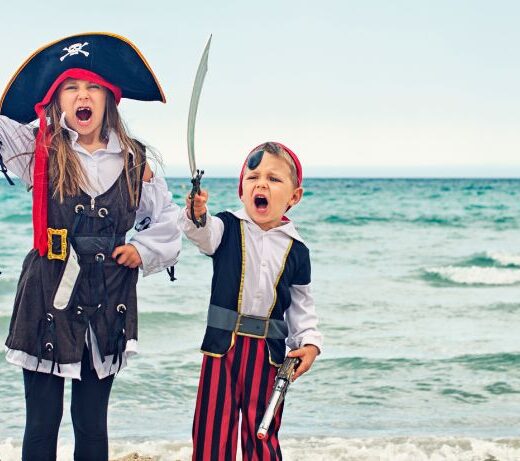 three kids dressed as pirates on a beach